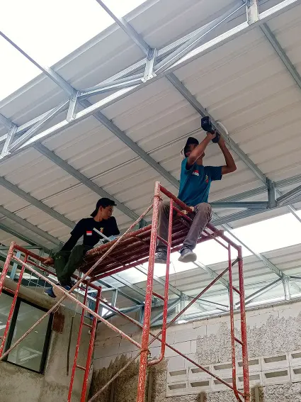 Teknisi listrik sedang memasang instalasi lampu industri