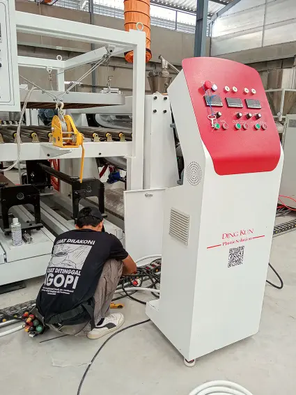 Teknisi listrik sedang memasang panel mesin extruder pabrik vinyl