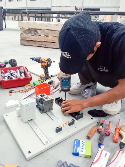 Teknisi listrik sedang merakit panel PFR mesin