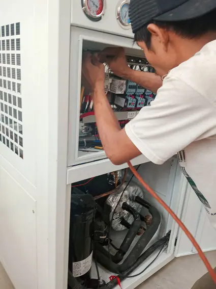 Teknisi listrik sedang melakukan perbaikan panel mesin chiller
