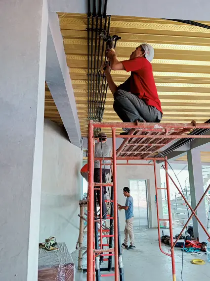 Tukang listrik sedang memasang pipa conduit untuk instalasi listrik gedung